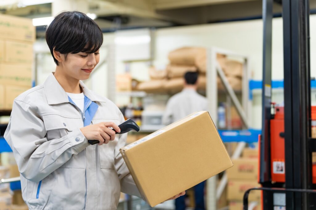 Eine Lagerarbeiterin scannt ein Paket mit einem MDE-Scanner, um den Versandprozess zu digitalisieren.